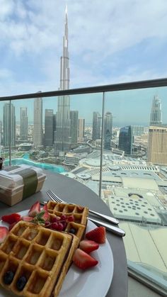 waffles and strawberries on a plate with a view of the burj