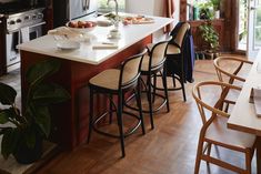 a kitchen with wooden floors and white counter tops next to an island in the middle