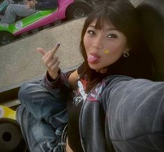 a woman sticking out her tongue while sitting in a car with other cars behind her