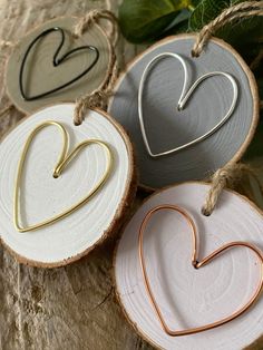 three heart shaped ornaments hanging from twine on wood slices with leaves in the background