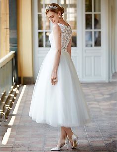 a woman in a white dress is standing on the sidewalk wearing a tiara and heels