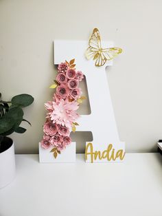 the letter a is decorated with pink flowers and gold letters, along with a butterfly