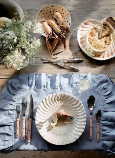 a table topped with plates and utensils next to food on top of a blue cloth