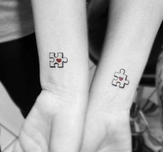 two people with matching tattoos on their arms holding each other's hands and one has a heart in the middle