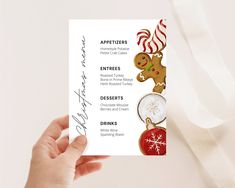 a person holding up a menu card with christmas decorations on it and an ornament in the shape of a gingerbread