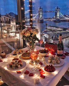 a table with food and drinks on it in front of a window overlooking the city