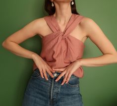 a woman standing in front of a green wall with her hands on her hips wearing a pink top