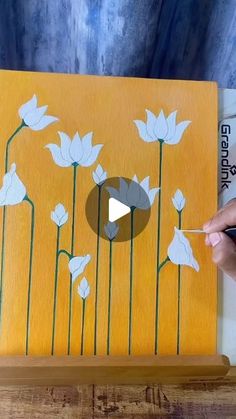 someone is painting flowers on a wooden board