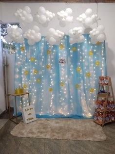 a blue and white backdrop with balloons hanging from it's sides, in front of a window