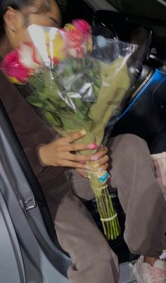 a woman sitting in the back seat of a car holding flowers