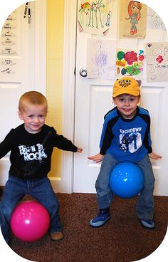 two young boys sitting next to each other on the floor with balloons in front of them