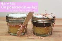 two small jars with cookies in them on a table next to a wooden spoon and twine