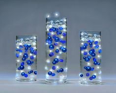 three glass vases with blue and white balls in them on a grey background,