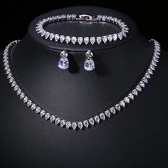 a necklace and earring set with clear crystal stones on a black display stand in front of a black background