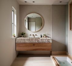 a bathroom with a sink, mirror and bathtub in the middle of the room