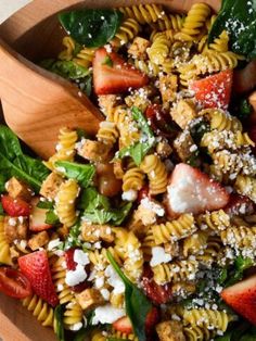 a salad with strawberries, spinach and feta cheese in a wooden bowl