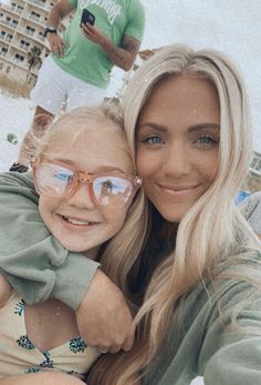 a woman taking a selfie with her daughter on the beach in front of some people