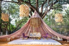 an outdoor seating area with pink drapes and chandelier hanging from the trees