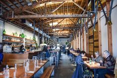 people sitting at tables in a restaurant with wooden walls and beams on either side of the room