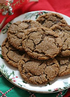 some cookies are on a white plate next to a red and green table cloth with christmas decorations