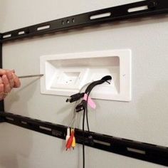 a man is holding a pair of scissors in front of a wall mounted electrical outlet