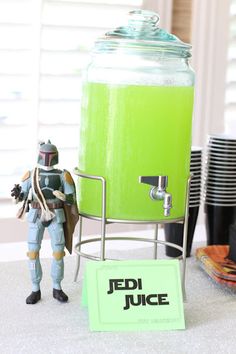 a star wars action figure next to a green juice dispenser