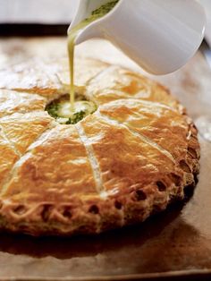 a person pouring sauce on top of a pie