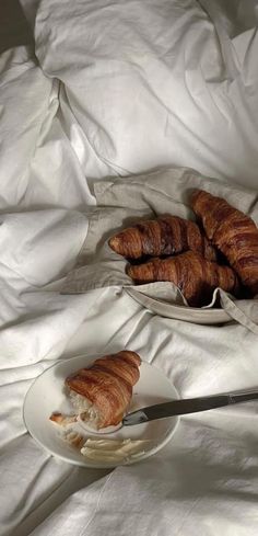 some croissants are sitting on a white plate and one is half eaten