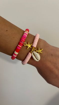 two bracelets with seashells and starfish charms on each arm, one in pink, the other in gold