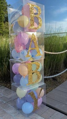 a clear acrylic box with balloons in it and the letters baa b