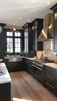 a large kitchen with black cabinets and stainless steel stove top oven, dishwasher, sink, and refrigerator