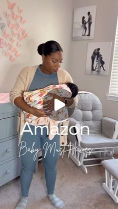 a woman holding a baby in her arms while standing next to a dresser and chair