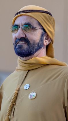 a man wearing a yellow headdress and green glasses is looking off to the side