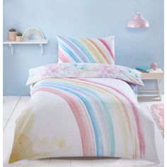 a bed with a rainbow colored comforter and pillow cases on top of it in a blue room