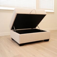 an open box sitting on top of a hard wood floor in front of a window