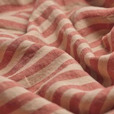 a red and white striped blanket is laying on the floor with it's edges folded