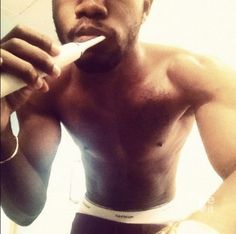 a shirtless man brushing his teeth with an electric toothbrush in front of him