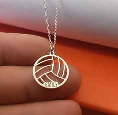 a person holding a necklace with a volleyball ball on it that says family in the center