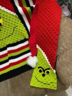 two crocheted christmas hats sitting on top of a couch next to each other