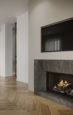 an empty room with a fireplace in the center and tv above it on the wall