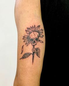 a person with a sunflower tattoo on their arm and the skull is in the middle