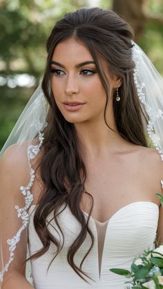 a woman in a wedding dress with a veil on her head and flowers around her neck