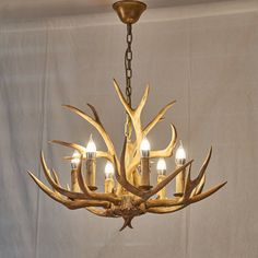 an antler chandelier with five candles in the center and four deer heads on it