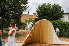 people are standing around and looking at a wooden structure that is shaped like a wave