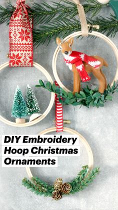 three christmas ornaments hanging from hoop with pine cones and evergreens on the top, one in red and white