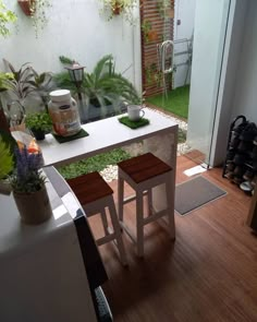 two stools sit in front of a table with plants on it and a potted plant next to it