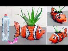 an orange fish planter with green plants in it and water bottle next to it