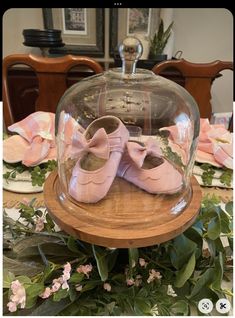 pink baby shoes under a glass dome on a table