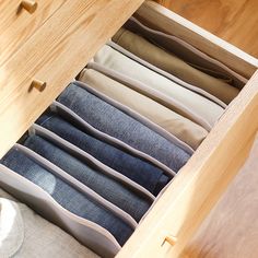 an open drawer with several pairs of jeans in it and the bottom section is empty