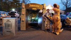 two people in animal costumes standing next to an entrance at night with cars parked behind them